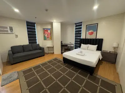 a bedroom with a bed and a couch at The Circuit Manor Hotel near Ayala Malls Circuit in Manila