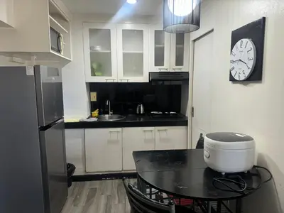 a kitchen with a table and a clock on the wall at Ladybyugs Condotel Rental in Manila