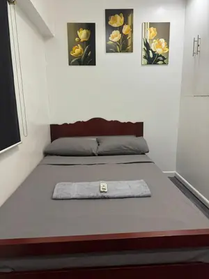 a bed in a room with three pictures on the wall at Ladybyugs Condotel Rental in Manila