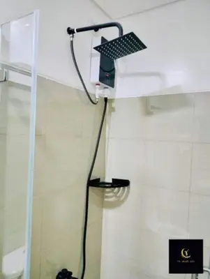 a shower in a bathroom with a light on the wall at Newly opened near MOA & Airport with PS4 and karaoke in Manila
