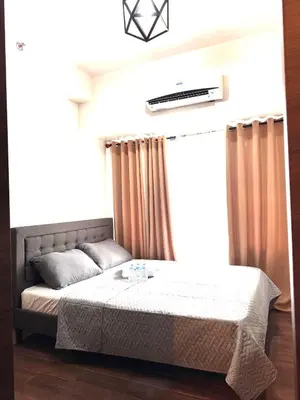 a bedroom with a bed and a window with curtains at Makati City Oasis The Air Residences #2148 in Manila