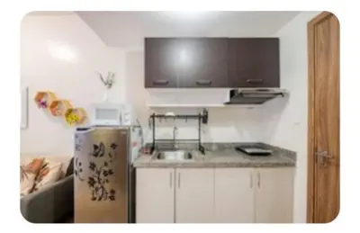 a small kitchen with a sink and a refrigerator at Benjamin's crib staycation in Manila