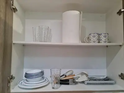 a kitchen shelf with plates and dishes on it at Sleek 1 BR APT at FAME Residences with Balcony in Manila