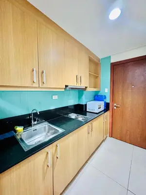 a kitchen with wooden cabinets and a sink at SGG Suite Room Pool View - Shell Residences MOA Pasay Near NAIA in Manila