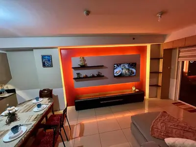 a living room with an orange accent wall at SGG Manila 2Bedroom MOA View - Shell Residences MOA Near Airport in Manila
