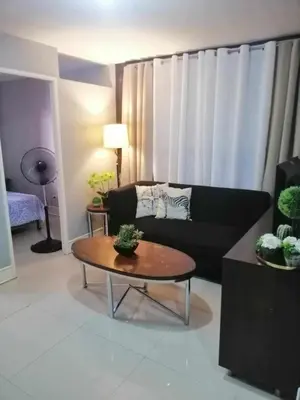 a living room with a black couch and a table at Royale 2BR Condo unit with free WiFi in Imus