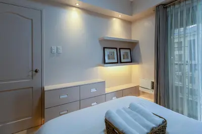 a bedroom with a large white bed with a window at 2br Forbeswood Heights in BGC near St Lukes in Manila