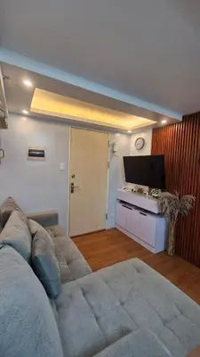 a living room with a couch and a flat screen tv at Cozy RC 2BR w loft Netflix Prime KTV Games in Manila