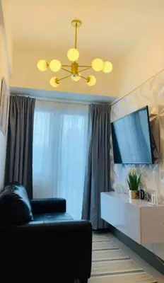 a living room with a black couch and a television at Cityscape Suite in Manila