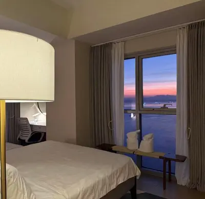 a hotel room with a bed and a large window at Playful 1BR With Magnificant Bayview Garden View Near Okada, Solaire, Aiports in Manila
