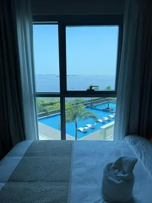 a bedroom with a large window with a view of a pool at Playful 1BR With Magnificant Bayview Garden View Near Okada, Solaire, Aiports in Manila