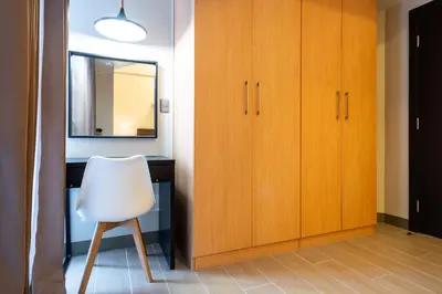 a white chair sitting next to a desk with a mirror at Uptown Parksuites Sky Garden Flr Bright Airy 2 BR balcony in Manila
