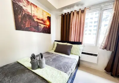 a bedroom with a bed with two shoes on it at RE Staycations in Manila