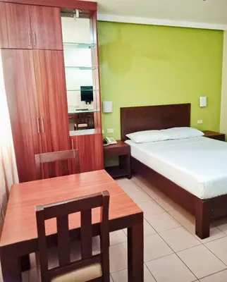 a bedroom with a bed and a table and a chair at Joyce Apartelle Mandaluyong in Manila