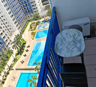 a balcony with a table and a view of a pool at Sea Residences-Booking Reservation in Manila