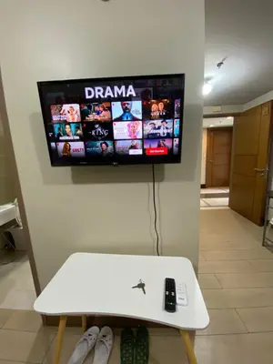 a tv on a wall with a remote control on it at the palm tree villas by kath in Manila