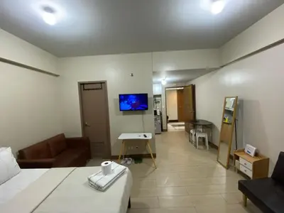 a room with a bed and a couch and a tv at the palm tree villas by kath in Manila
