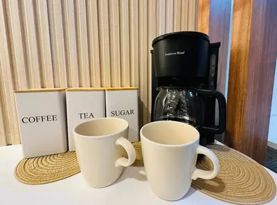 two coffee cups sitting on a table next to a coffee maker at Getaway Haven at Southwoods, Biñan with Fast Internet in Biñan