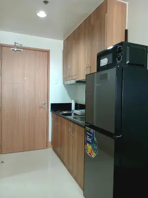 a kitchen with a black refrigerator and wooden cabinets at Condo Next Door PH in Manila