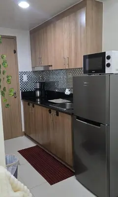 a kitchen with a stainless steel refrigerator and wooden cabinets at SMDC Red Residences Makati w own parking slot in Manila