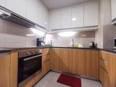 a kitchen with wooden cabinets and a stove top oven at Bayshore Staycation in Manila