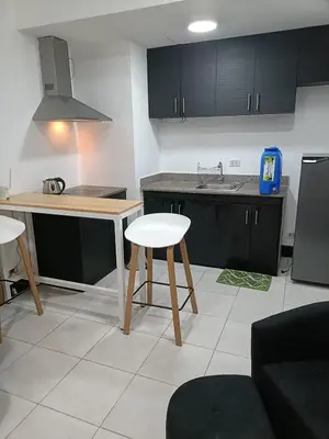 a kitchen with black cabinets and a table and stool at A place to relax & have privacy in Manila