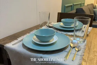 a table with two blue bowls and plates and glasses at The Shoreline Suite at Shore 3 Residences MOA Pasay in Manila