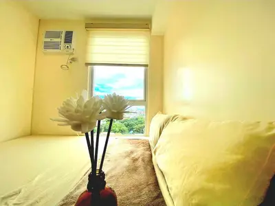a bedroom with a bed and a vase with flowers in it at Veronica Grey's Staycation 2BR in Manila