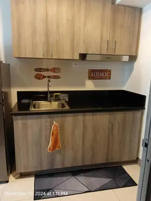 a kitchen with wooden cabinets and a sink at Coast Residences in Manila