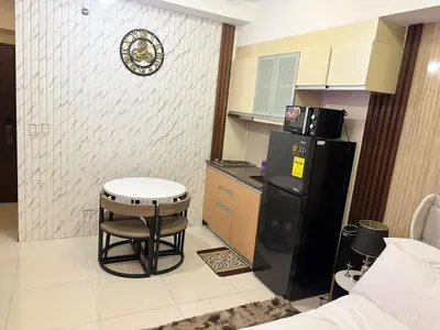 a small kitchen with a black refrigerator and a stool at Cozy Studio near BGC Super Fast Wi-Fi in Manila