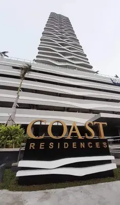 a tall building with a sign in front of it at Coast Residences in Manila