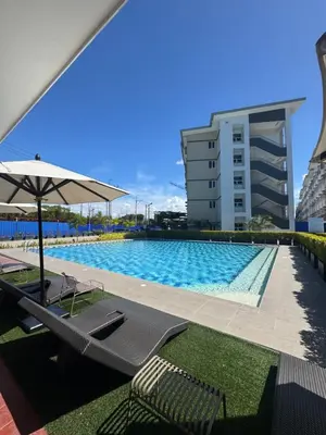 a swimming pool with chairs and an umbrella and a building at SMDC Park Residences Unit 202 in Ibaba