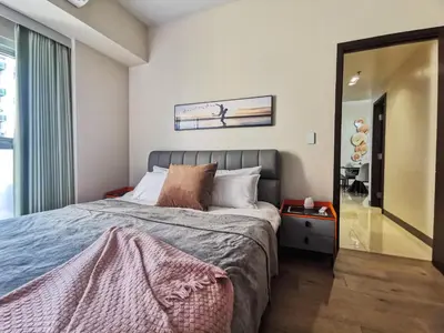 a bedroom with a large bed and a mirror at Modern Condo in Prime Location in Manila