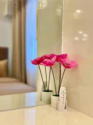 two pink flowers sitting on a table in a room at Elegant Staycation Near Mall of Asia with Pool Access in Manila