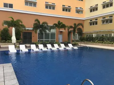a swimming pool with lounge chairs and a building at Happy Nook at Holland Park Condominium in Biñan