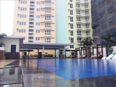 a swimming pool in front of two tall buildings at Happy Nook at Holland Park Condominium in Biñan