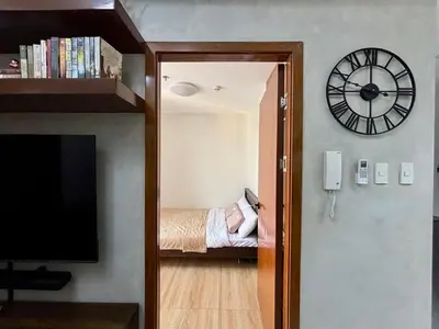 a room with a clock and a bedroom with a bed at Condo in Mandaluyong with BGC Skyline in Manila