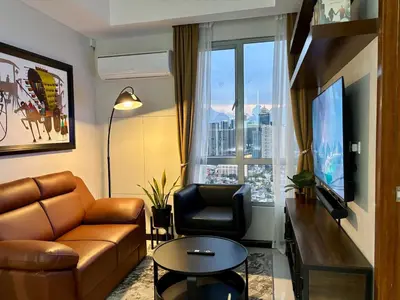 a living room with a couch and a chair and a window at Condo in Mandaluyong with BGC Skyline in Manila