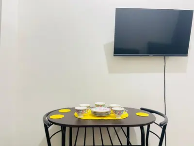 a table with three cups and plates and a tv at Cozy condotel Field Residence in Manila