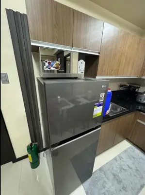 a kitchen with a stainless steel refrigerator and wooden cabinets at JRM Staycation The Radiance Manila Bay Sunset with Pay Parking in Manila