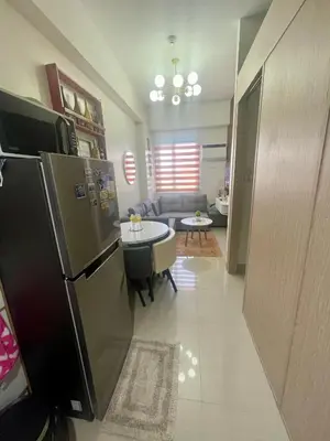 a kitchen with a refrigerator and a living room at Empirestatecation at Leaf Residences in Manila