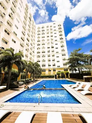 a swimming pool in front of a large building at JFam Suites, C4-10R Studio, Up To 4 Pax in Biñan