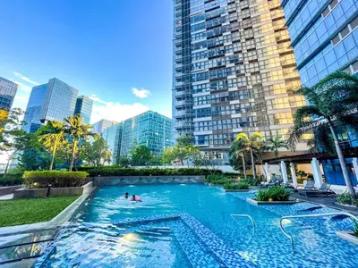 a large swimming pool in a city with tall buildings at Rare 3BR Modern Penthouse in BGC II Sleeps 12pax in Manila