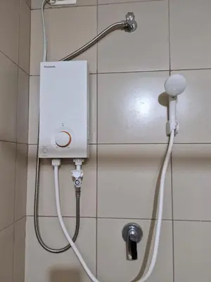 a shower with a hose attached to a wall at Your 2BR within Pasay in Manila