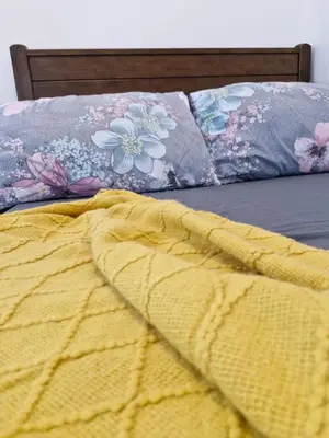 a bed with a yellow blanket and floral pillows on it at Your 2BR within Pasay in Manila