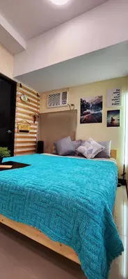 a bedroom with a large bed with a blue blanket at 2 Unique Side-by-Side Studios Vibrant & Zen at Viceroy BGC in Manila