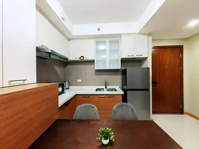a kitchen with white cabinets and a wooden table at 1BR Condotel Suite at Sunshine100 City Plaza #SS02-1 in Manila