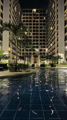 a large building with palm trees in front of it at Affordable Stay in MOA in Manila