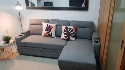 a grey couch with pillows in a living room at Very Spacious Condo at Mall of Asia in Manila