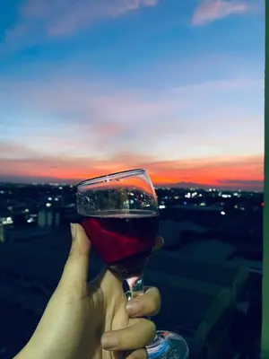 a person holding up a glass of wine at sunset at Azure staycation by scarlet suites in Manila